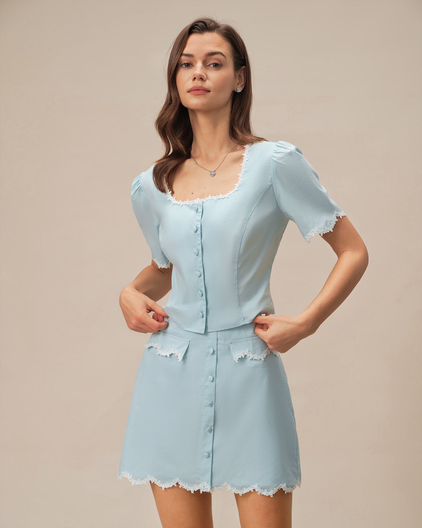 Blusa azul‑claro de renda com botões e decote quadrado